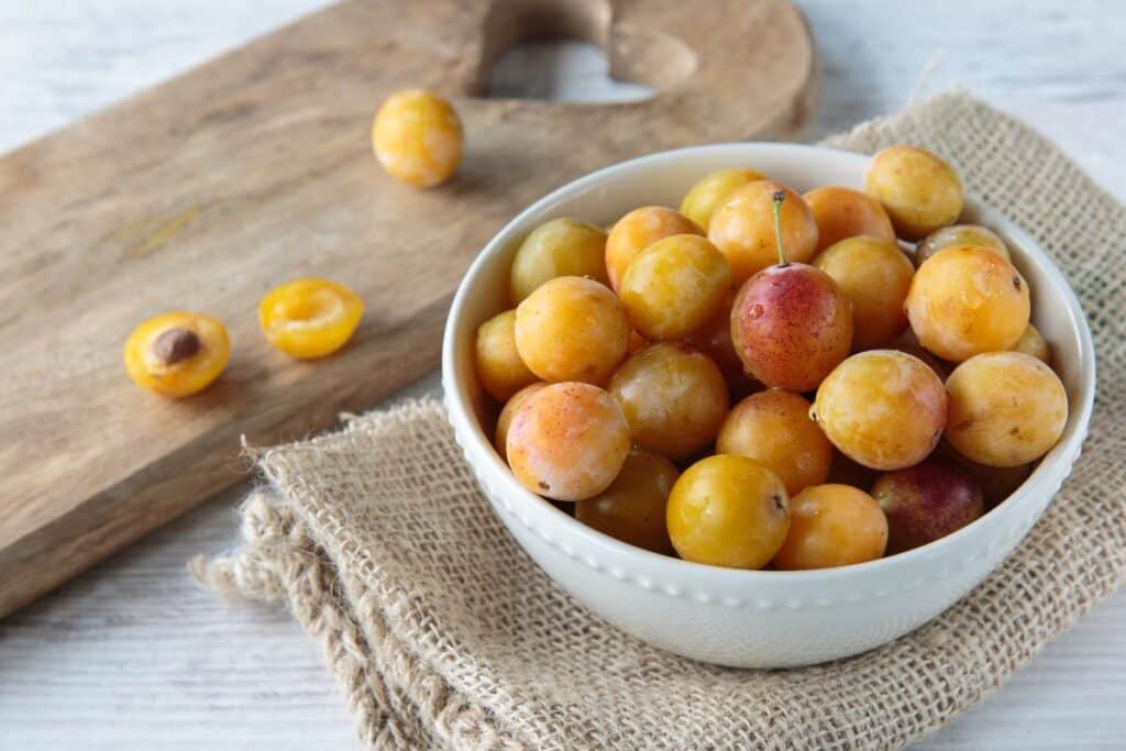 Bol de mirabelles sur une planche en bois.