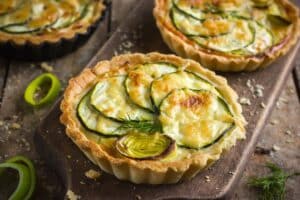 Tarte aux courgettes et poireaux sur planche en bois.