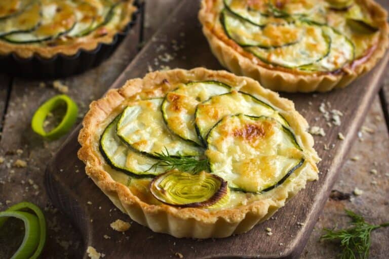 Tarte aux courgettes et poireaux sur planche en bois.
