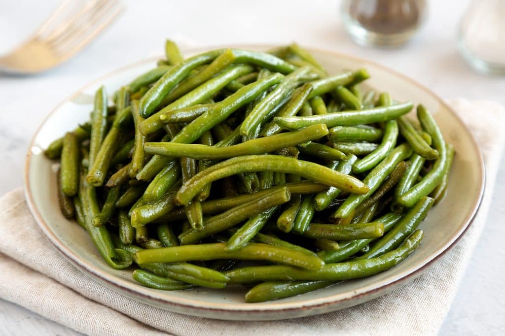 homemade sauteed green beans on a plate, side view.
