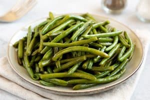 homemade sauteed green beans on a plate, side view.